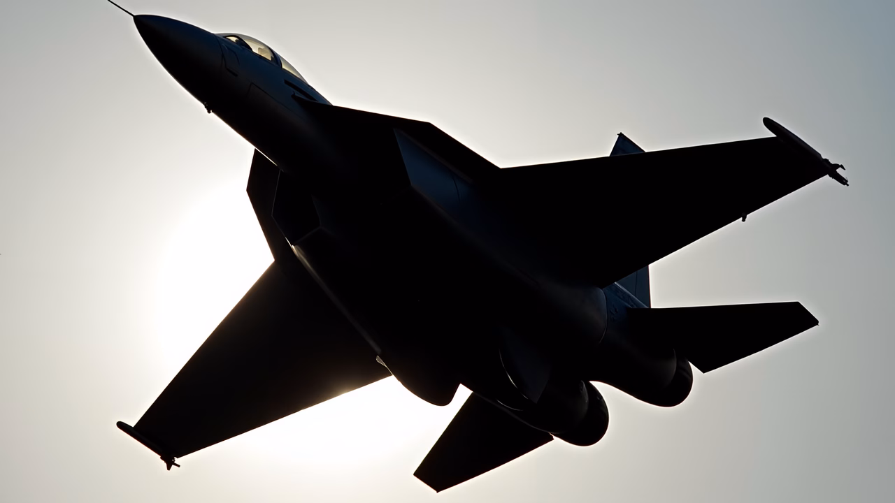 Silhouette of a fighter jet against a bright sky, emphasizing power and speed.