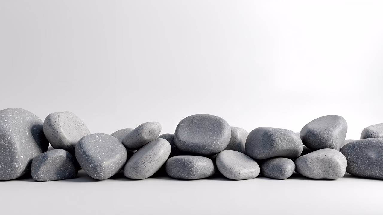 Minimalistic arrangement of smooth gray pebbles on a white background.