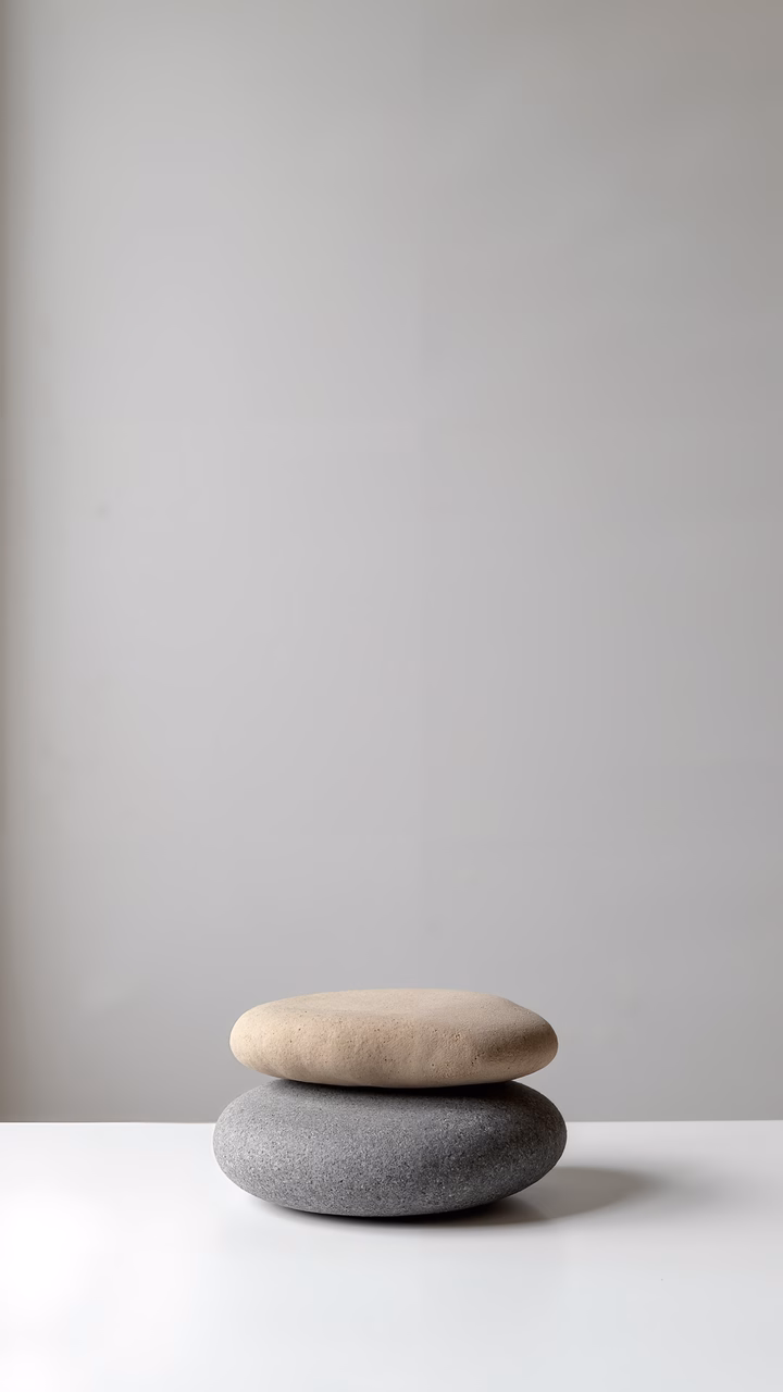 Minimalist photograph of balanced stones against a white backdrop.