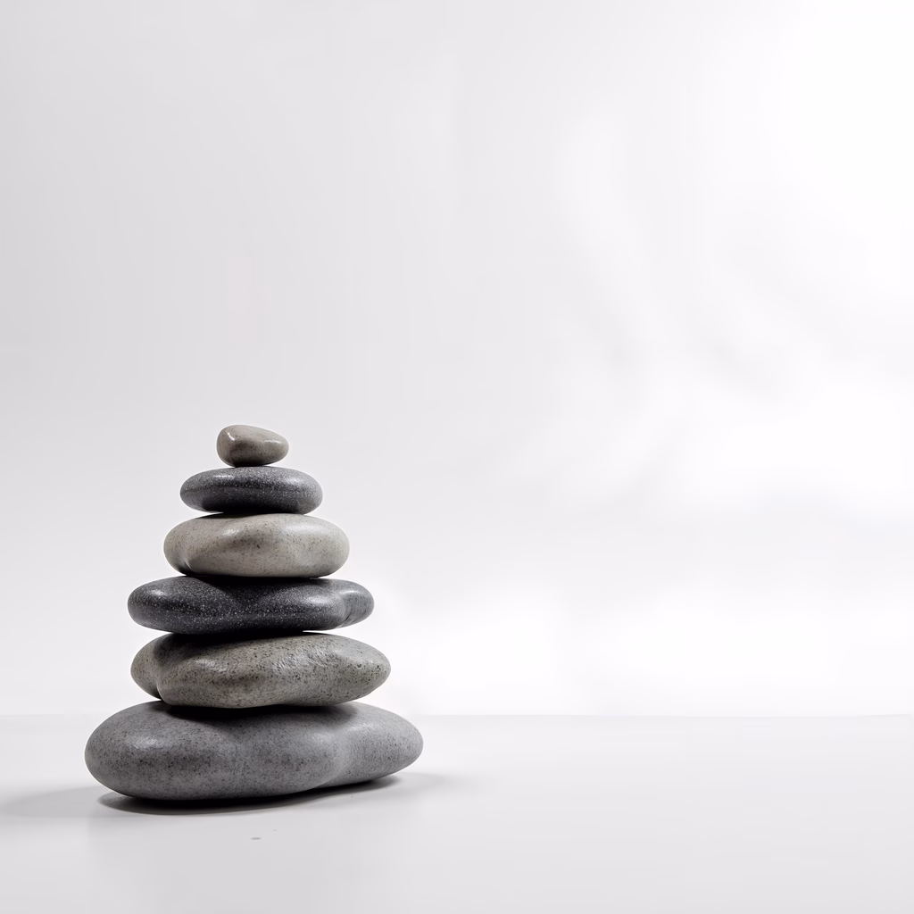 Minimalist stone stack against a white backdrop, symbolizing balance and tranquility.