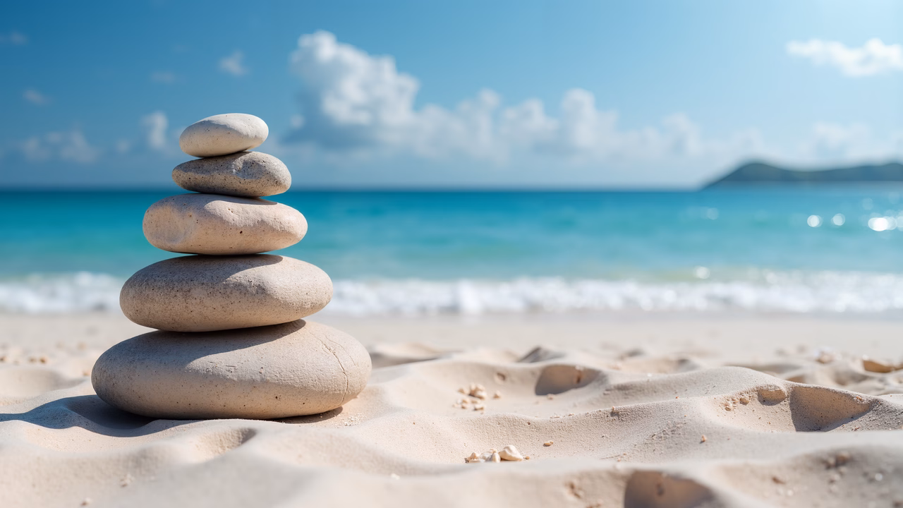 Balanced stones on a sunny beach, evoking peace and tranquility.