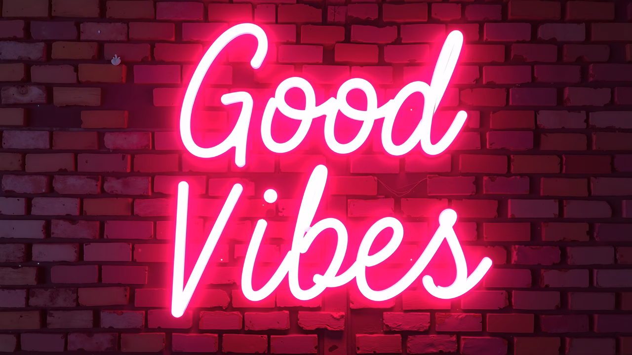 Vibrant neon sign saying 'Good Vibes' on a brick wall.
