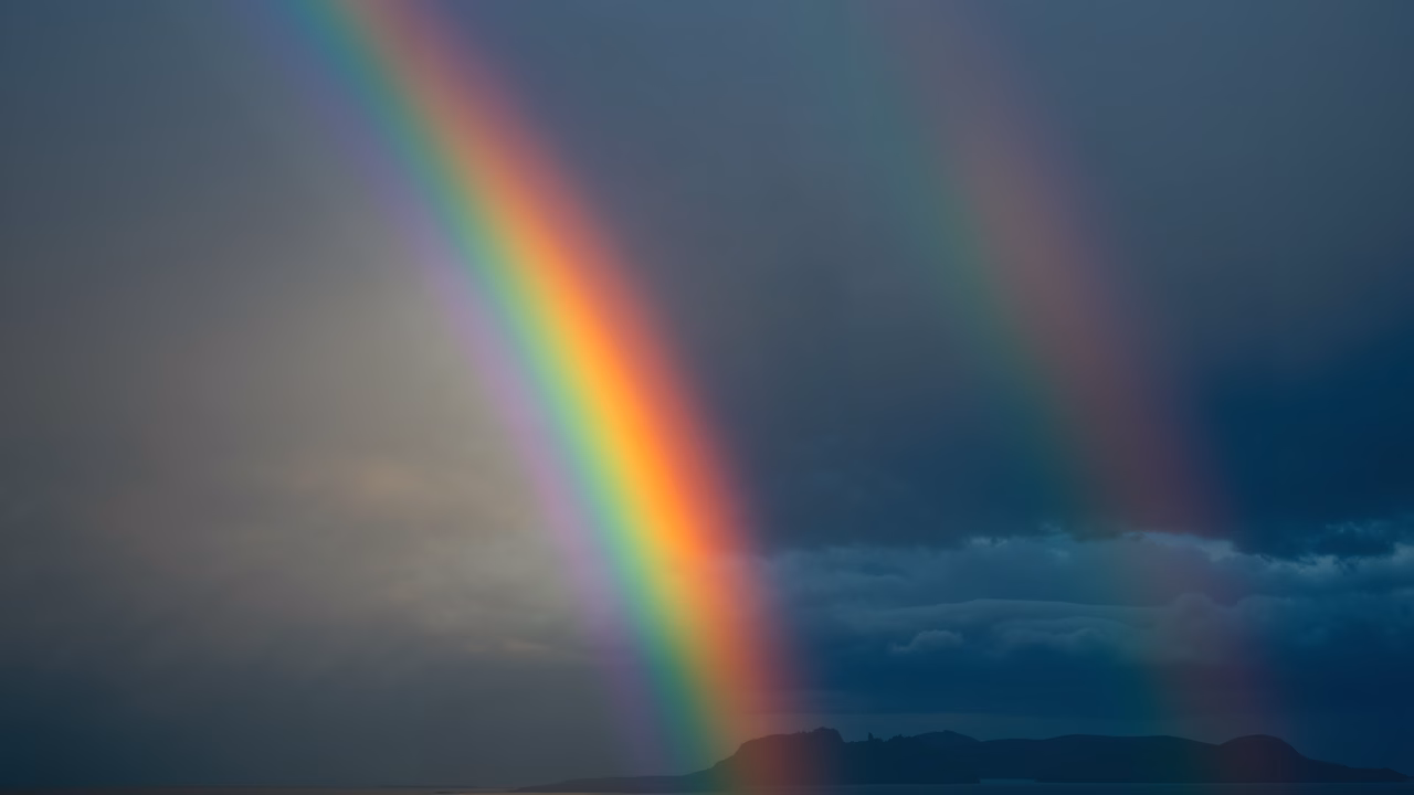 A stunning double rainbow over a cloudy horizon, capturing nature’s beauty and tranquility.