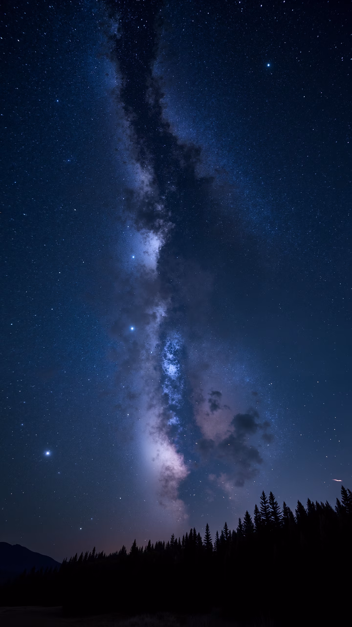 A breathtaking view of the Milky Way over a forest silhouette under a starlit sky.