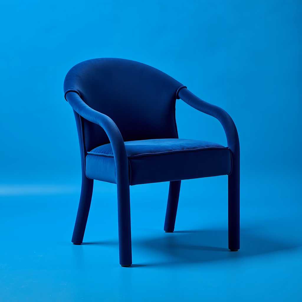 A luxurious blue velvet chair against a monochromatic blue background.