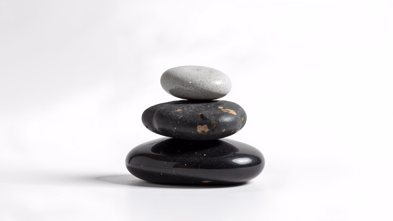 Minimalist still life photography featuring stacked stones against a white backdrop.