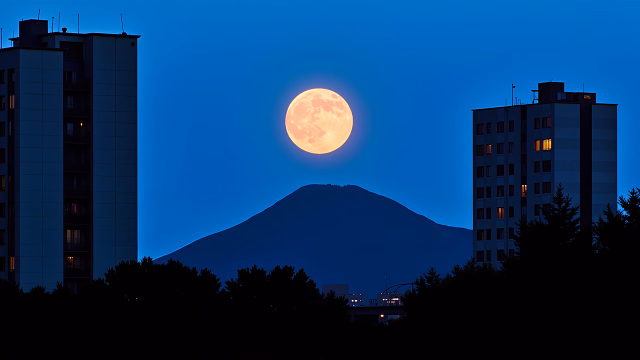Full moon rising over city skyline at dusk, serene urban landscape.