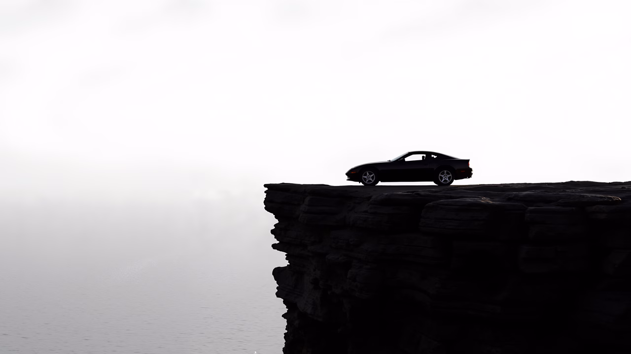 Solitary car on misty cliff overlooking calm sea