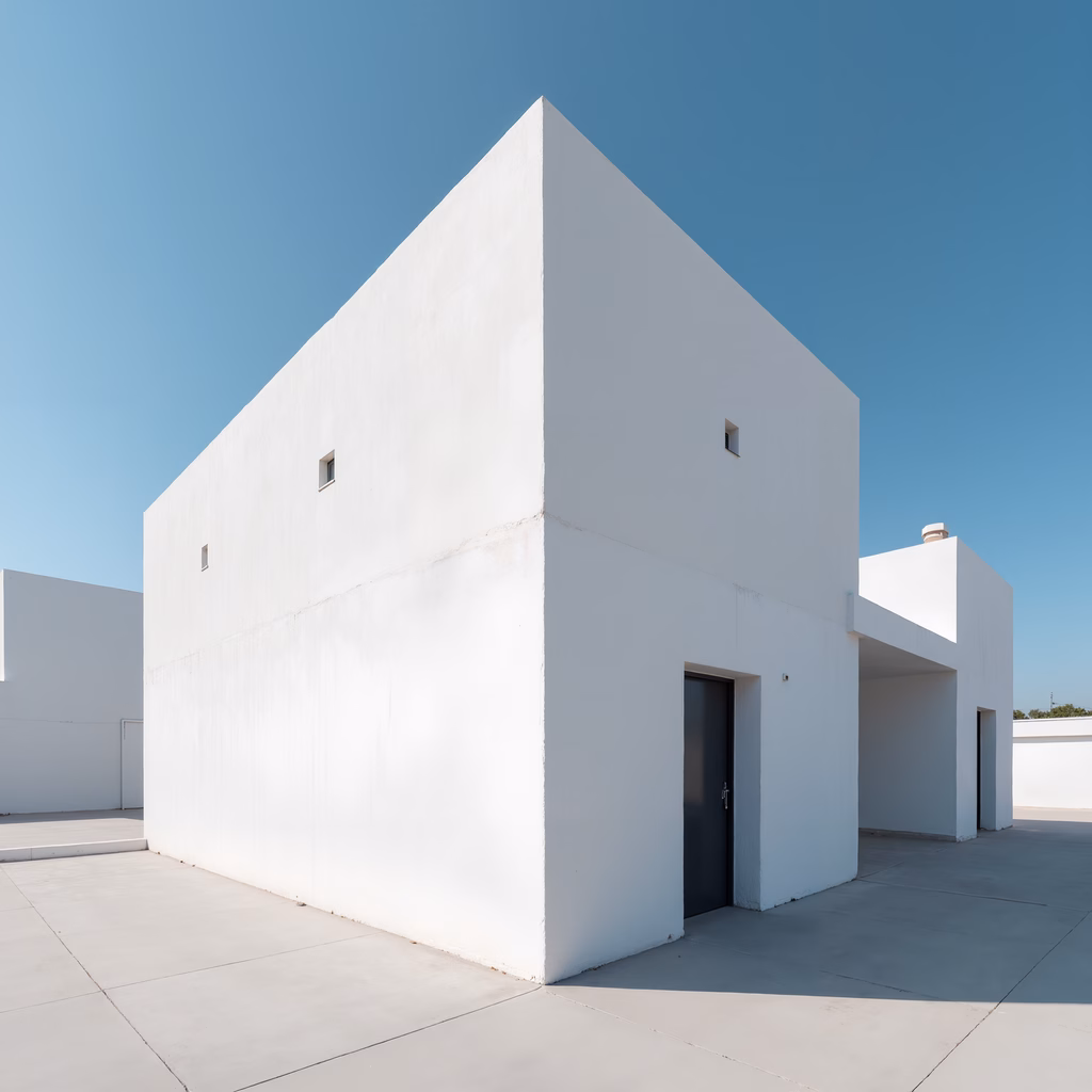 Minimalist white house with stark contrast against a clear blue sky