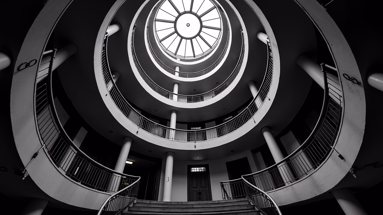 Black-and-white spiral staircase with dramatic lighting and symmetrical design.
