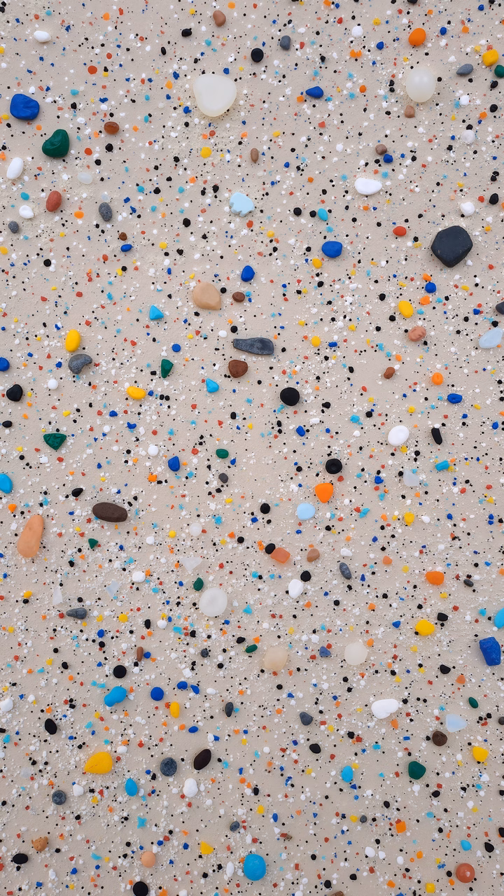 Close-up of colorful pebbles on a sandy beach.