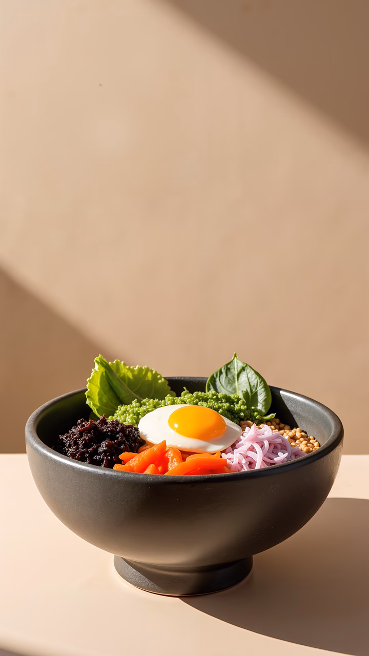 A beautifully arranged bibimbap bowl with fresh ingredients and warm lighting.