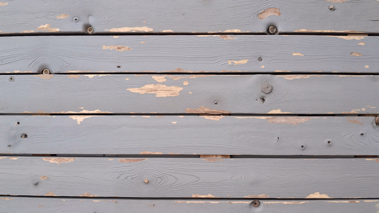 Close-up of weathered wooden planks with muted gray tones and visible grain patterns.