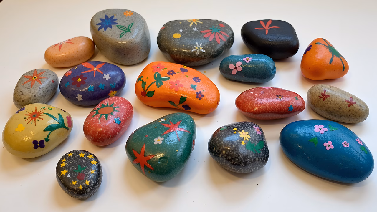 Colorful painted rocks arranged on a white background.