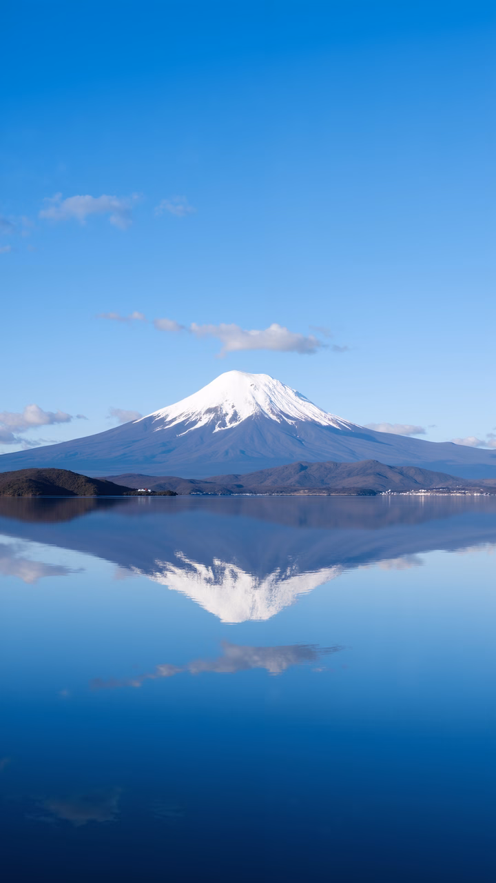 Symmetrical reflection of Mount Fuji against a clear blue sky, capturing tranquility and natural beauty.