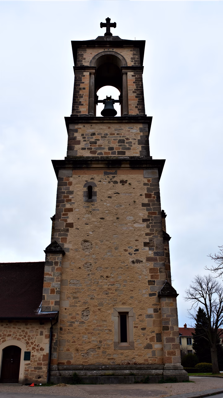 Stone church tower with bell against cloudy sky