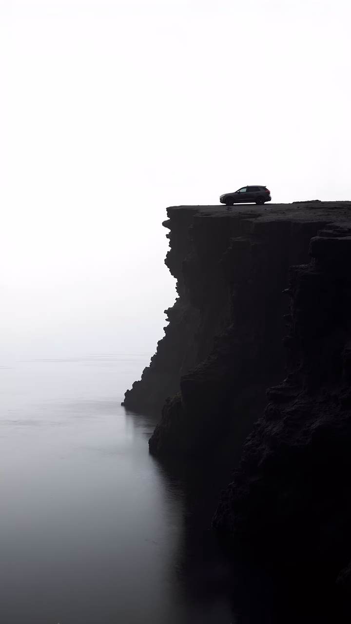 Solitary car on cliff overlooking foggy sea, evoking a sense of solitude and introspection.