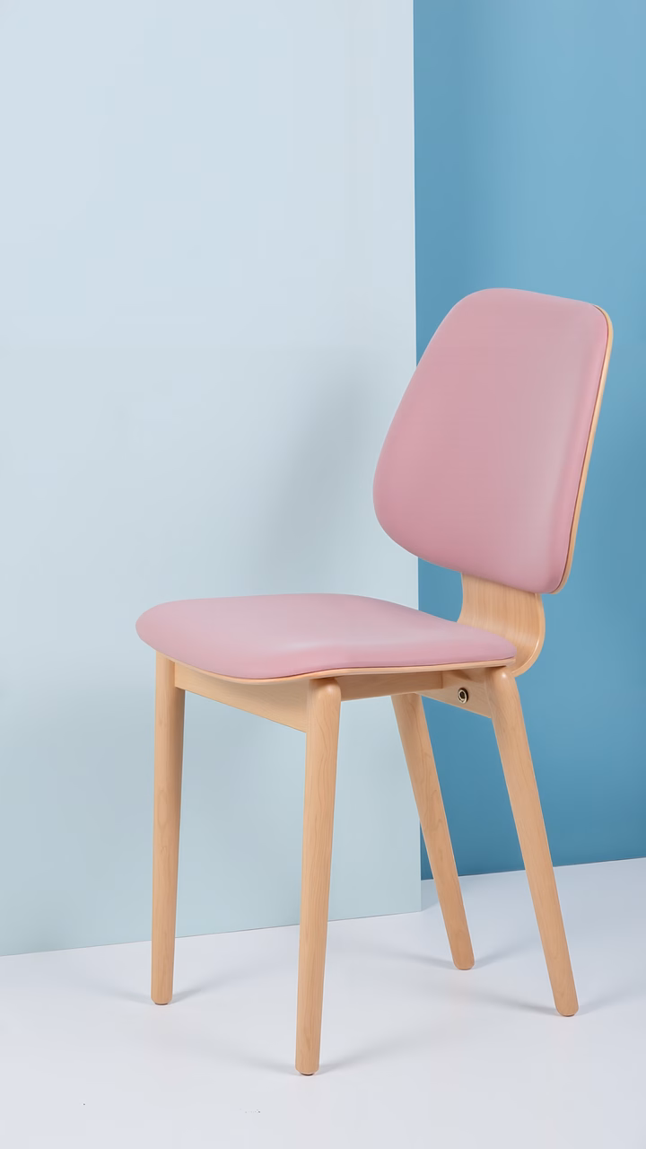 Minimalist pastel chair design with wooden legs against a two-tone wall backdrop.