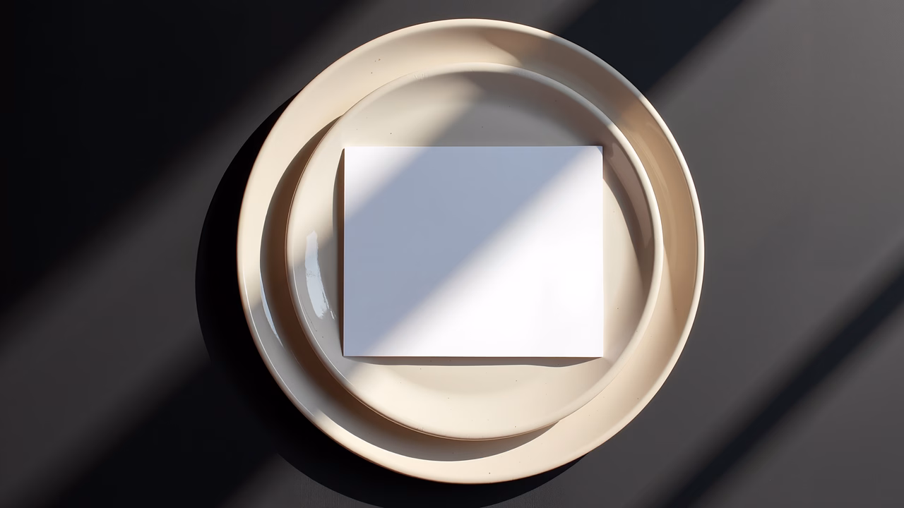 Minimalist still life with stacked plates and white paper in natural light.