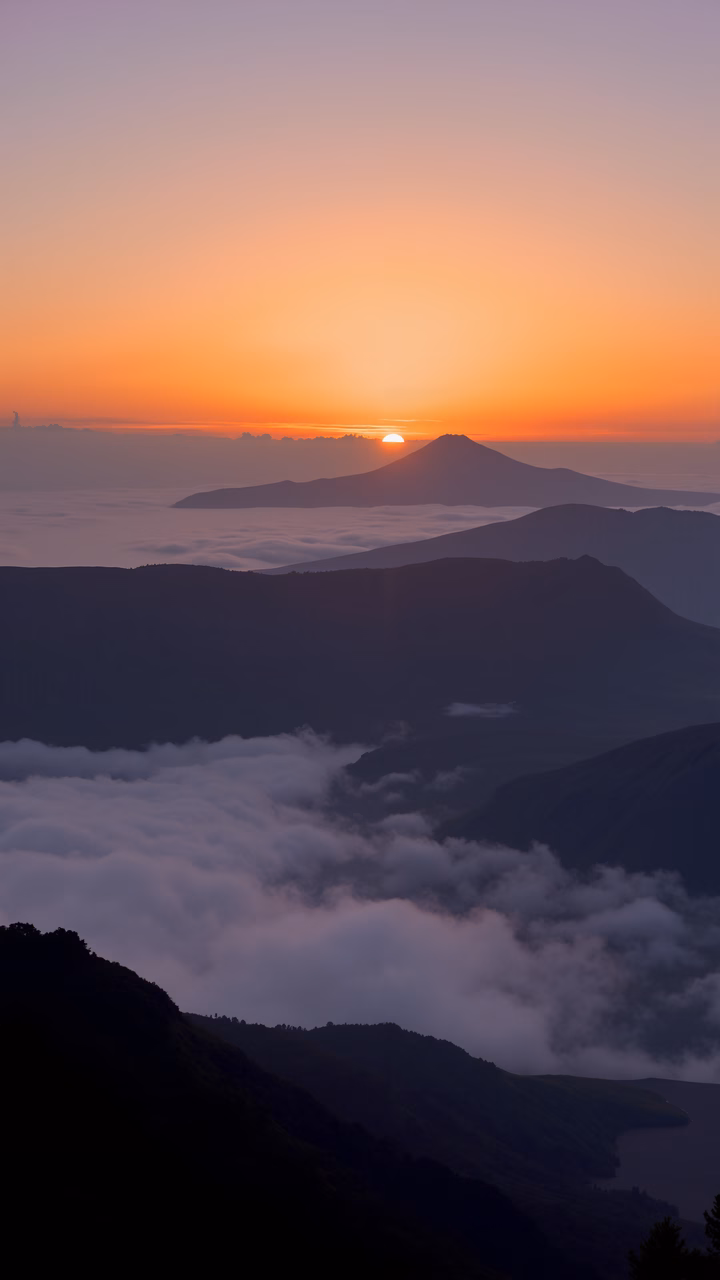 Sunset over mountains with vibrant colors and tranquil clouds.